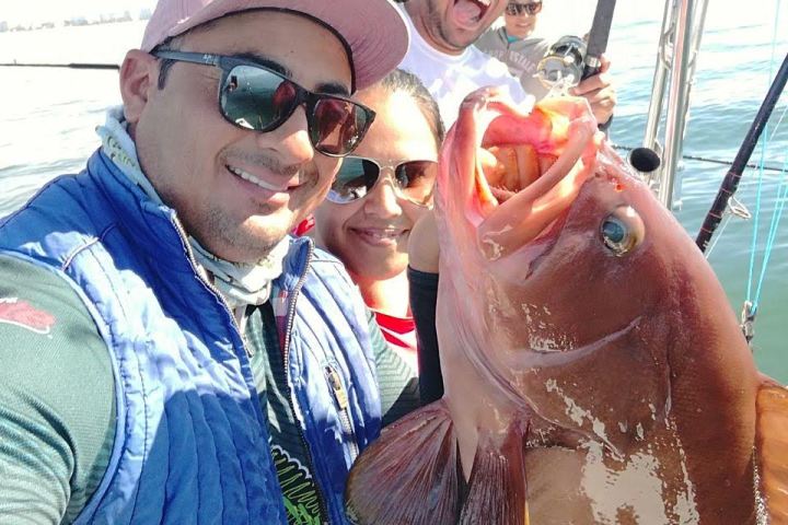 a person wearing a hat and sunglasses holding a fish