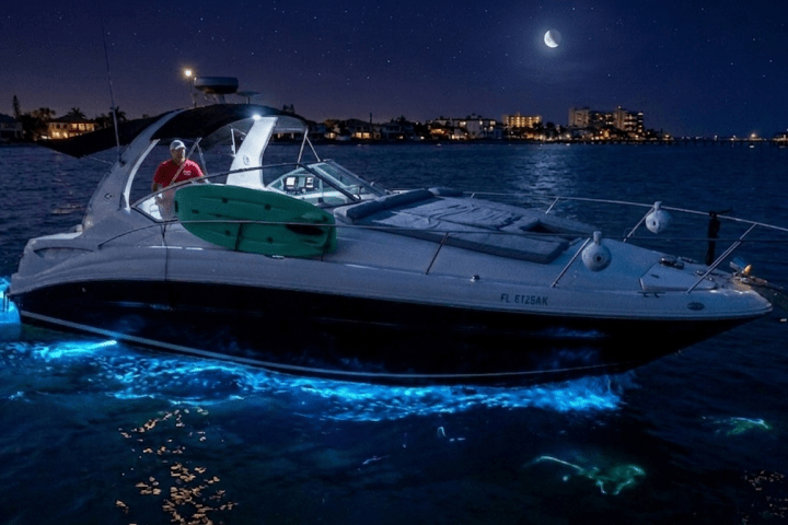 Boat with glowing water at night under a crescent moon.