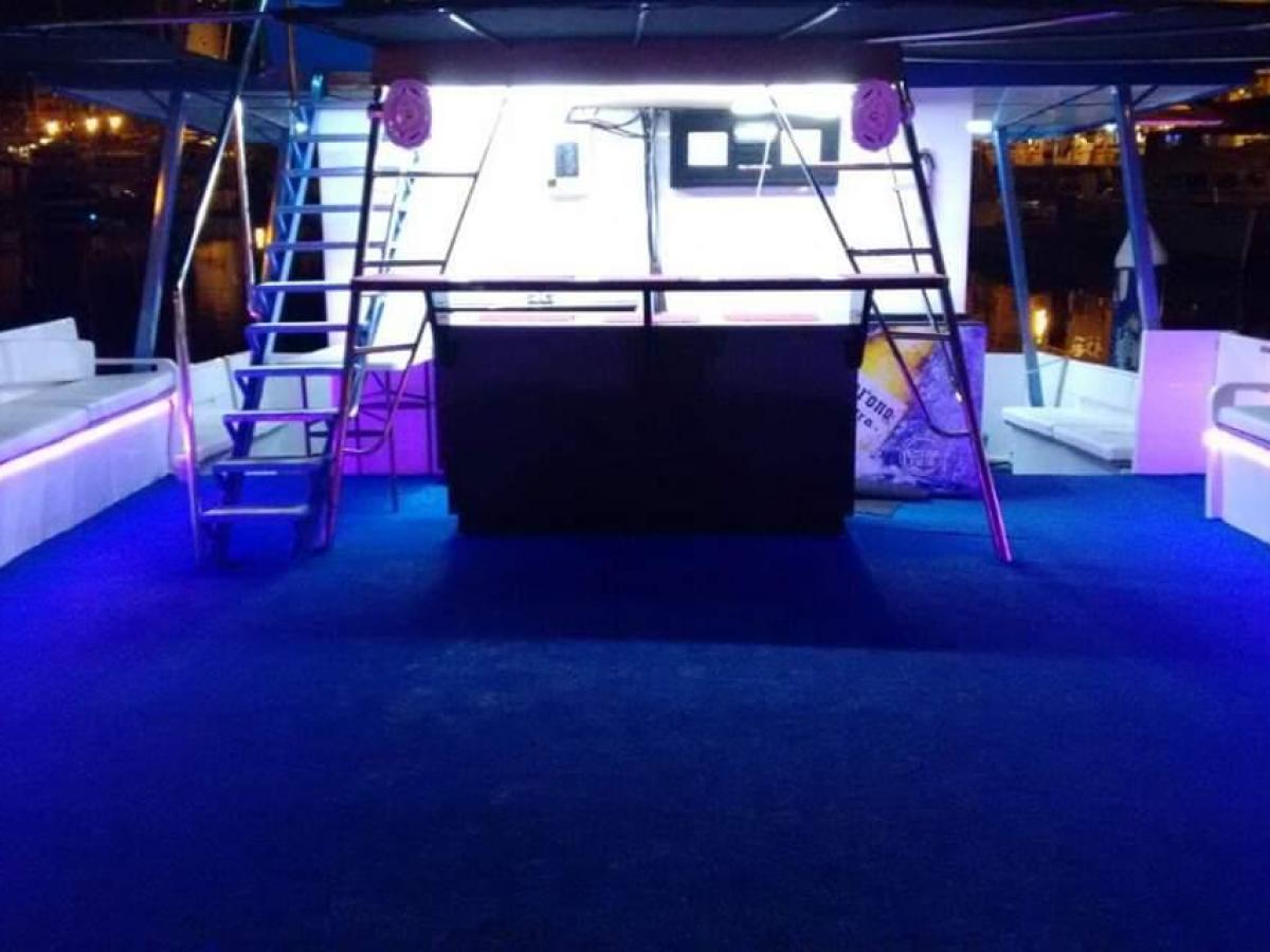 Illuminated boat deck with blue LED lights and white benches at night.