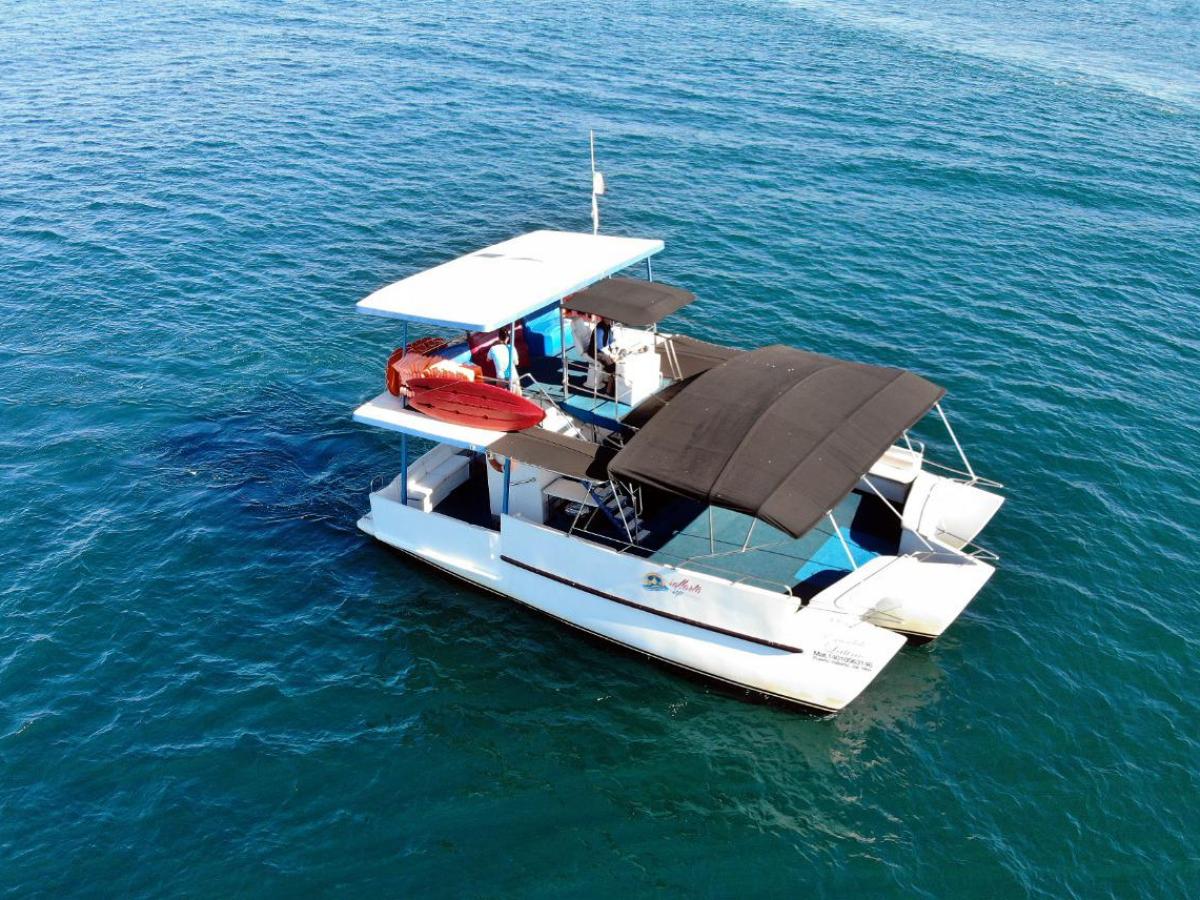 White boat with black canopy and red kayak on roof, floating on blue water.