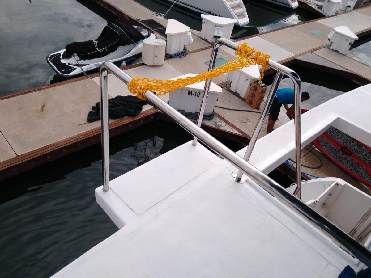View from boat deck with yellow rope on railing at a marina.
