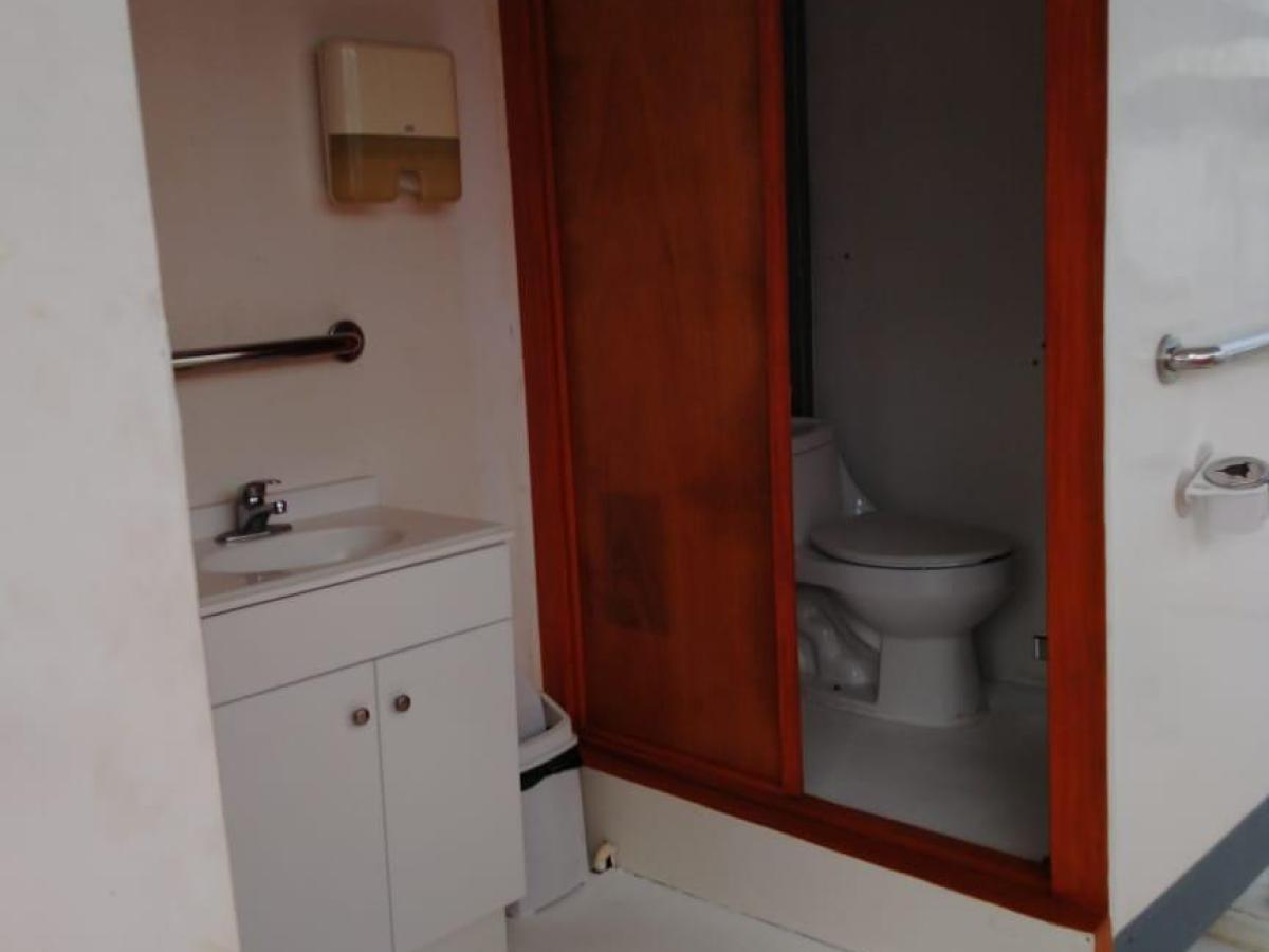 White restroom with sink, paper dispenser, and toilet in a separate stall.