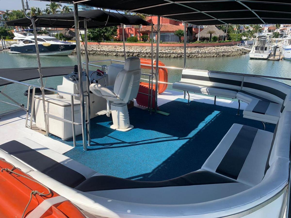 Open deck of a boat with seating and a steering area on a calm marina.
