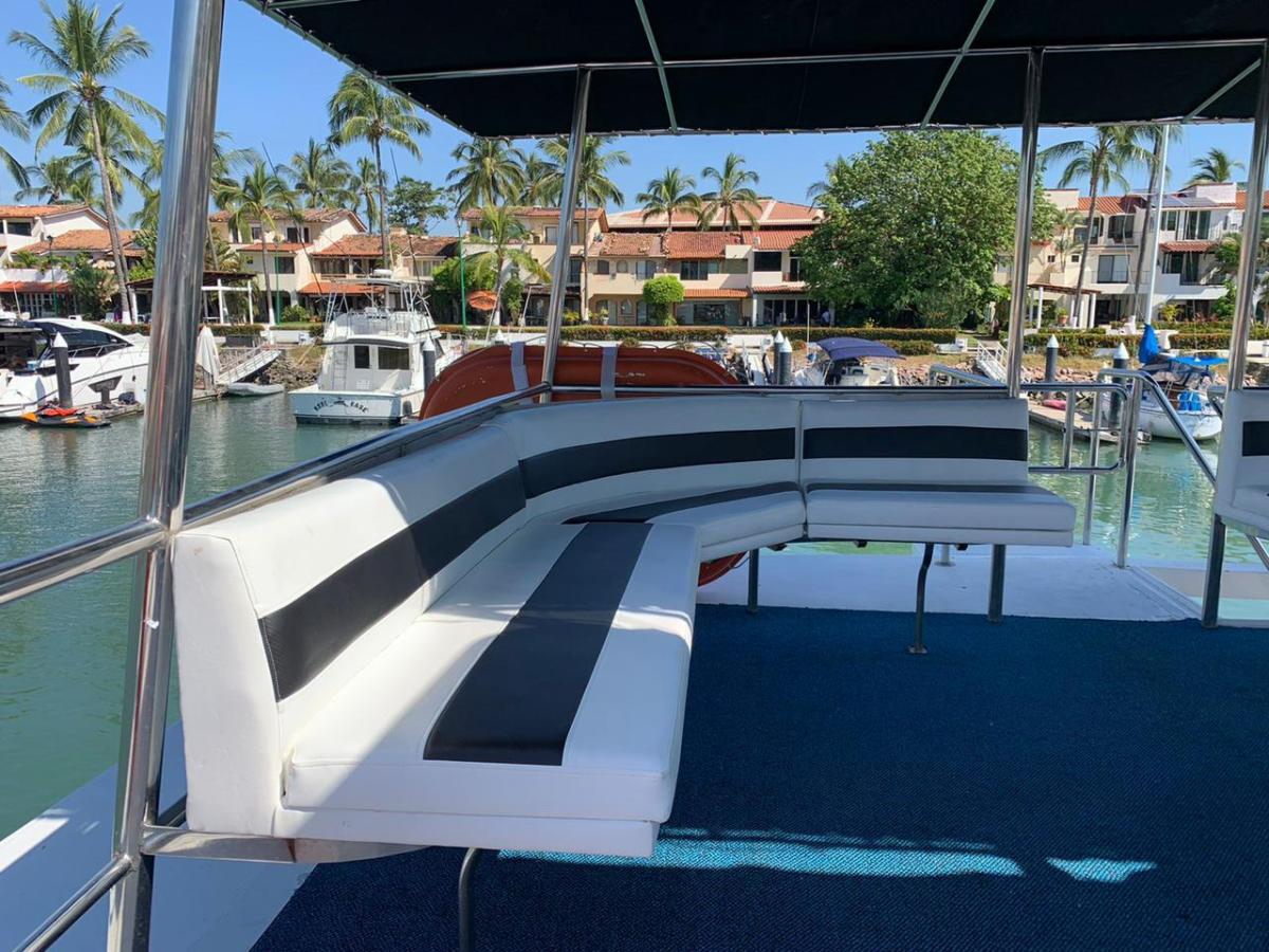 Boat deck with white and black seating, overlooking a marina.