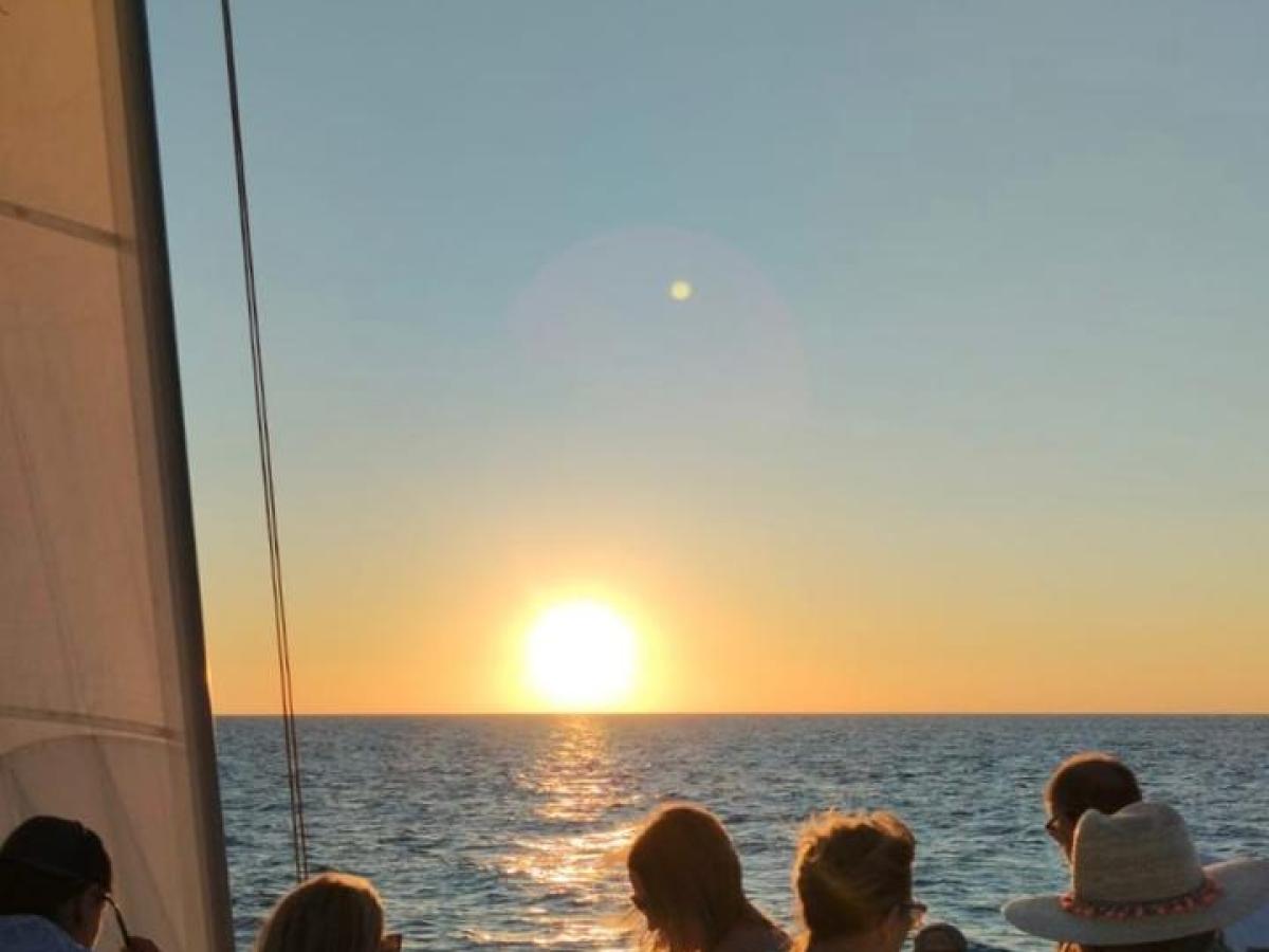 a group of people sitting next to a body of water