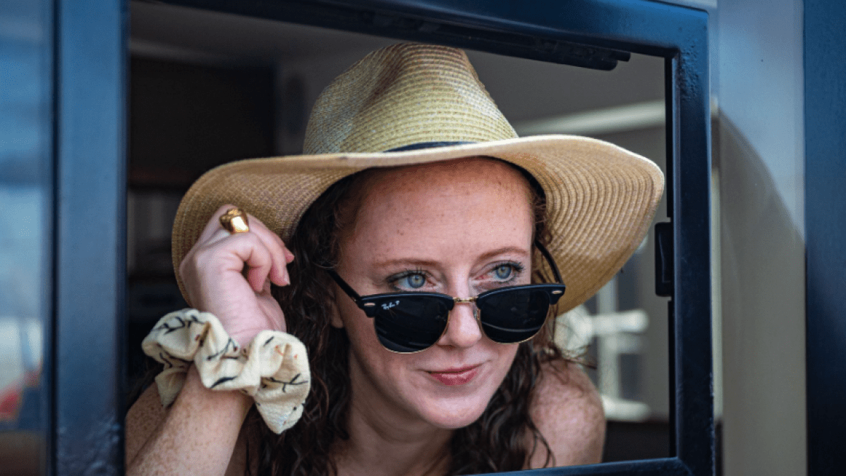 a person wearing a hat and sunglasses posing for the camera