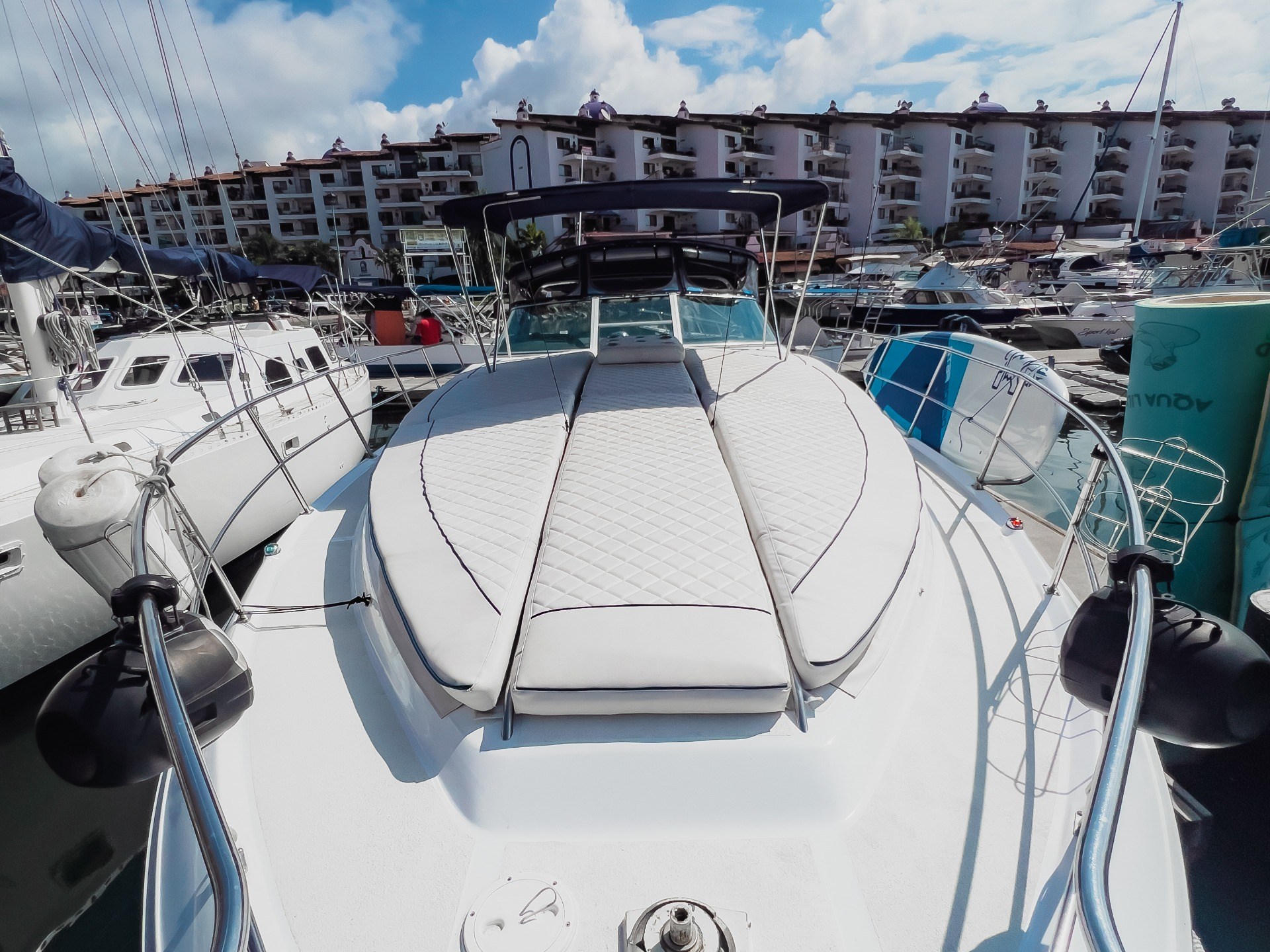 View from a yacht's bow facing a marina with a clear blue sky.