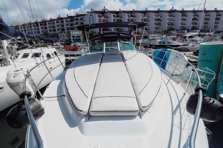 View from a yacht's bow facing a marina with a clear blue sky.