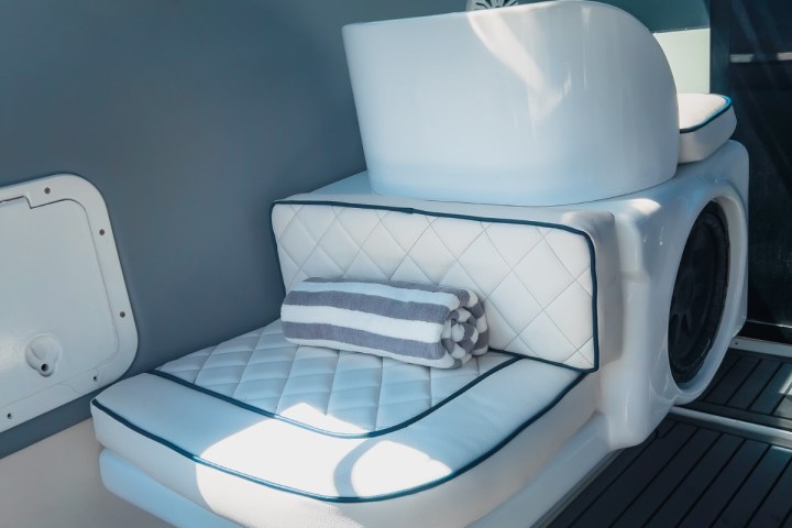 Luxury boat seat with white quilted cushion and striped towel, next to a window showing blue sky.