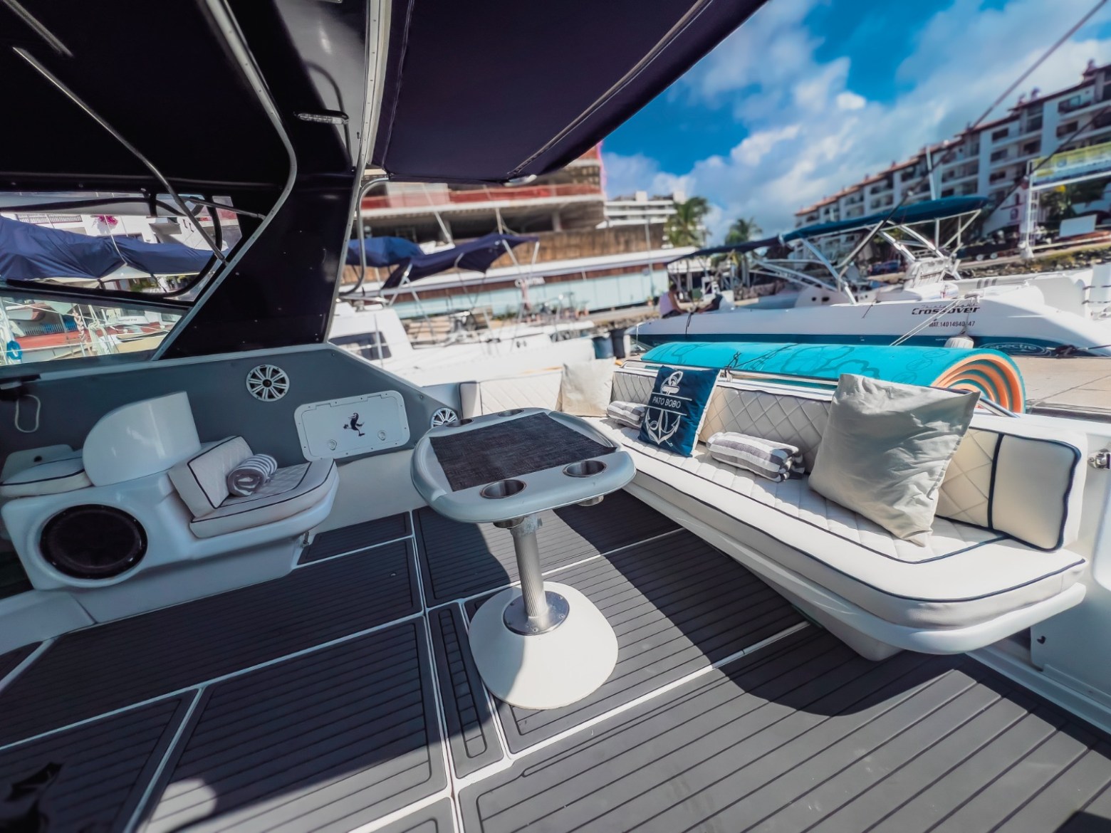 Luxurious yacht deck with cushioned seating, table, and marina view.