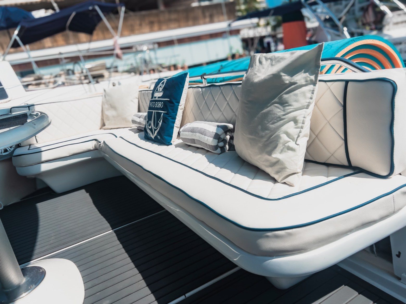 White boat seats with pillows and a draped towel in a marina setting.