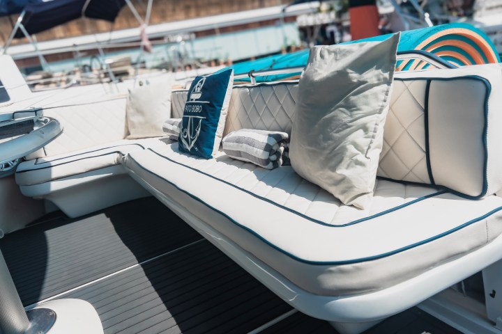 White boat seats with pillows and a draped towel in a marina setting.
