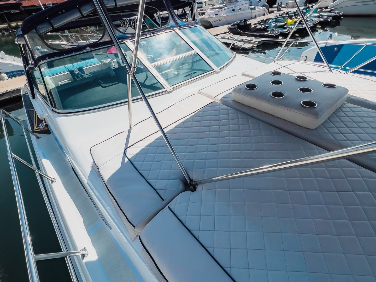 Yacht deck with cushioned seating, canopy, and marina view in the background.