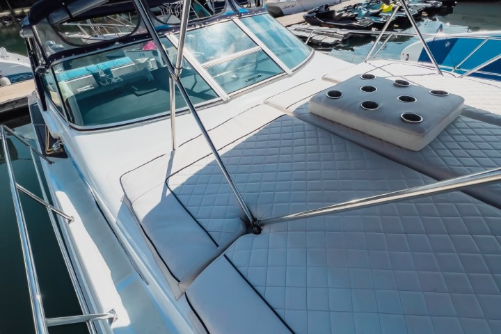 Yacht deck with cushioned seating, canopy, and marina view in the background.