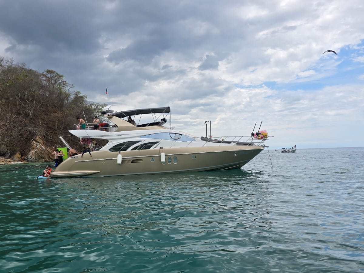Luxury yacht on calm sea near rocky shoreline under cloudy sky.