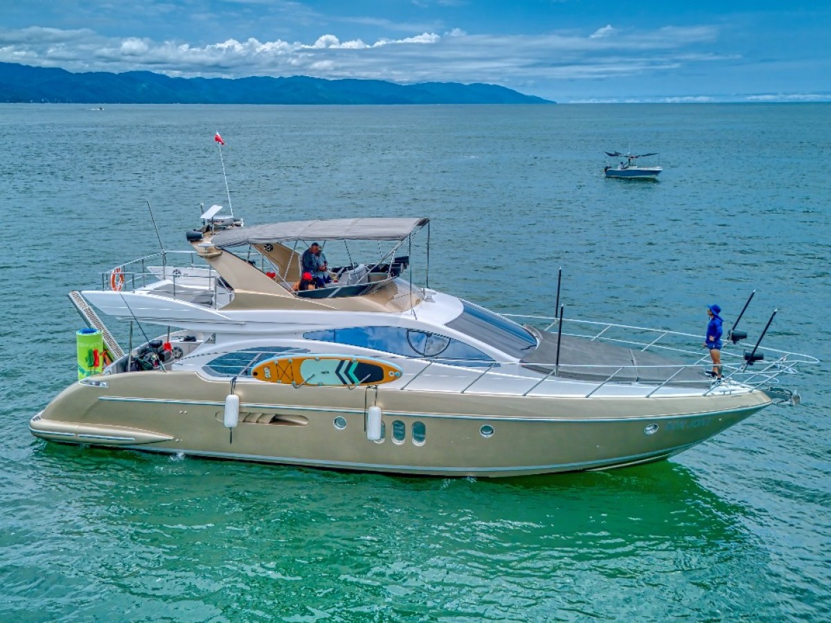 Luxury yacht on calm sea with hills in the background.