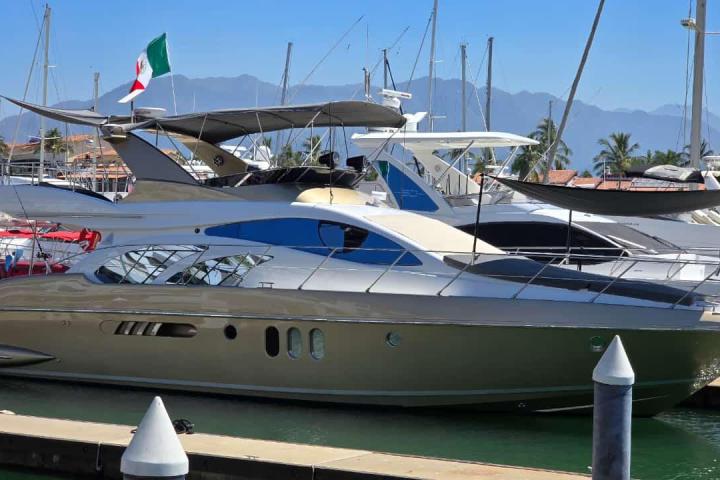Luxury yachts docked in a marina with mountains in background.