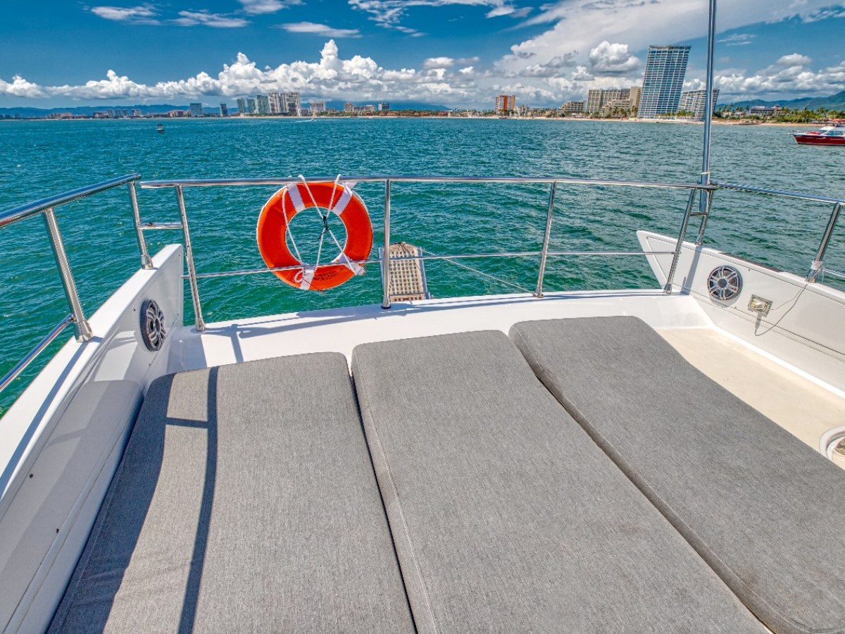 View from boat deck with cushions, facing ocean and city skyline.