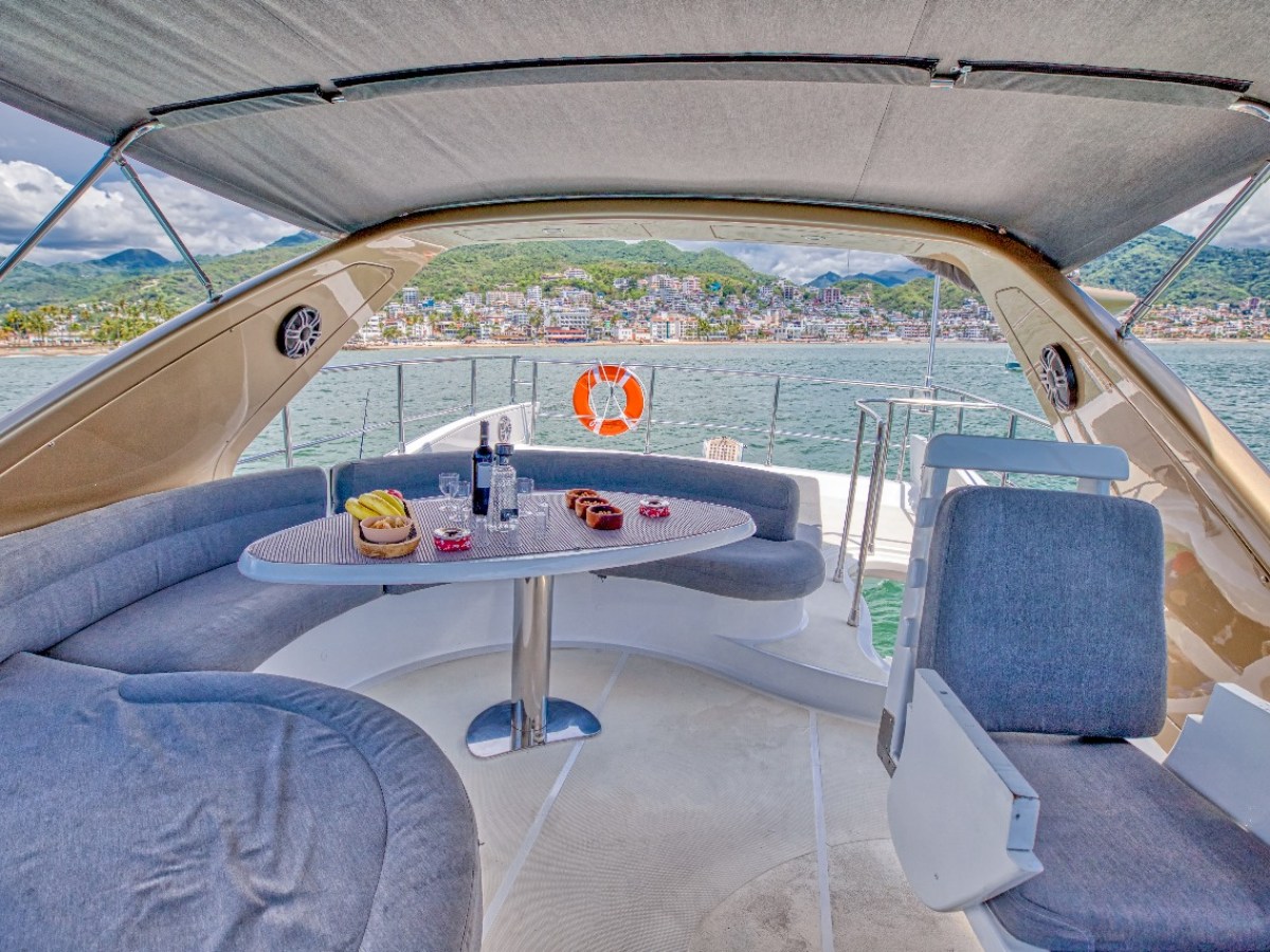 View from a yacht's seating area with a table, sea and coastal town in the background.