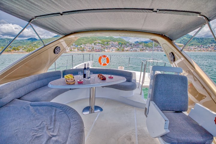 View from a yacht's seating area with a table, sea and coastal town in the background.