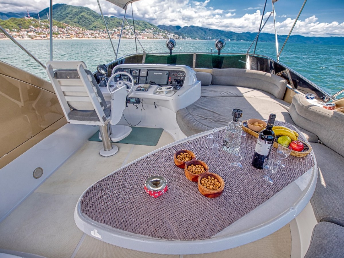 Luxury yacht deck with helm, snacks, wine, and sea view.