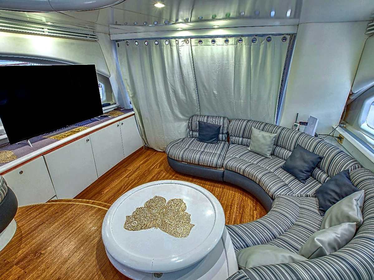 Modern yacht interior with a curved striped sofa and a large TV.