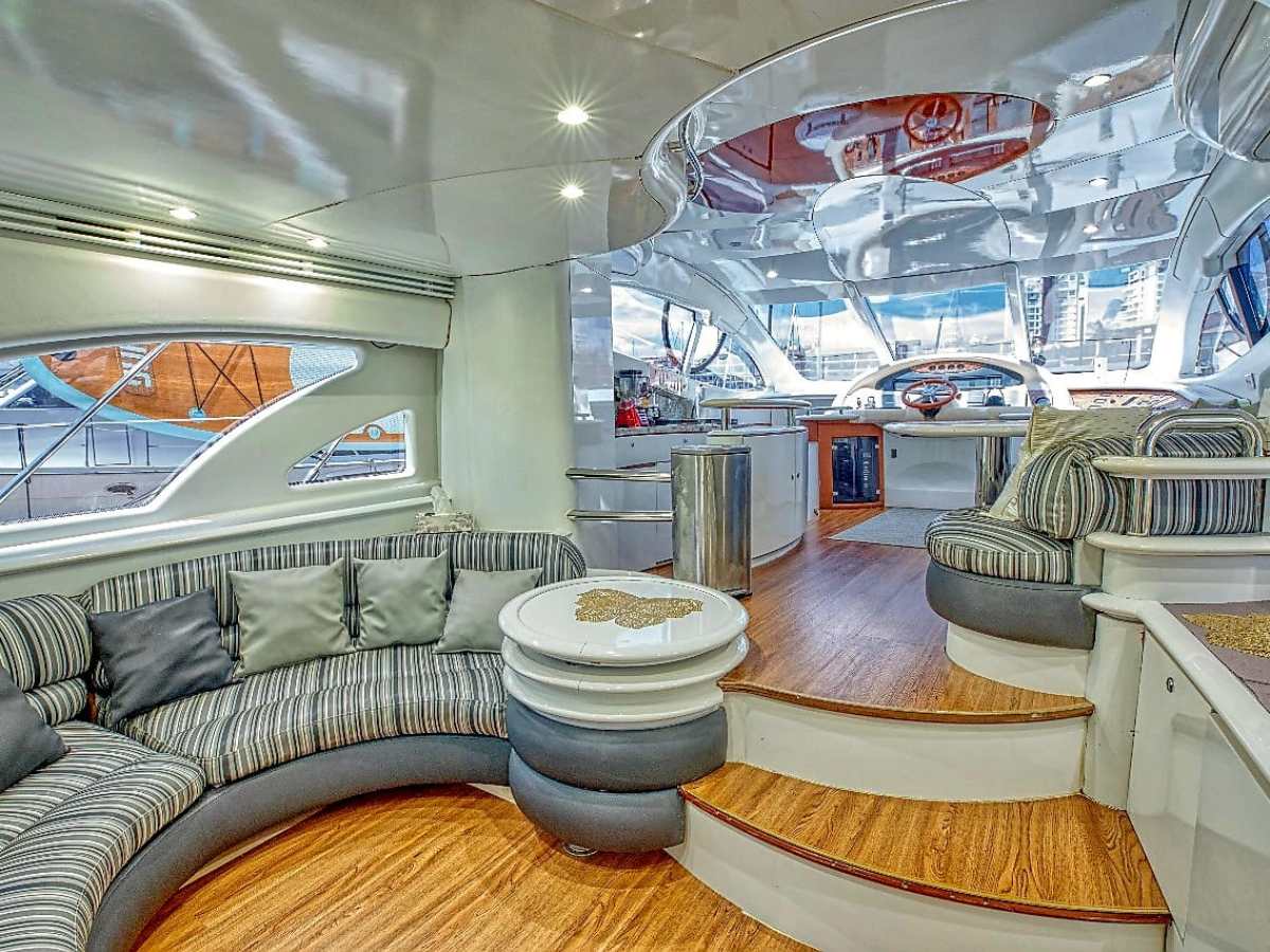 Luxurious yacht interior with curved seating, wooden flooring, and modern windows.