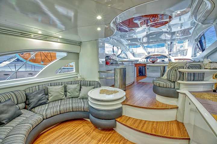 Luxurious yacht interior with curved seating, wooden flooring, and modern windows.