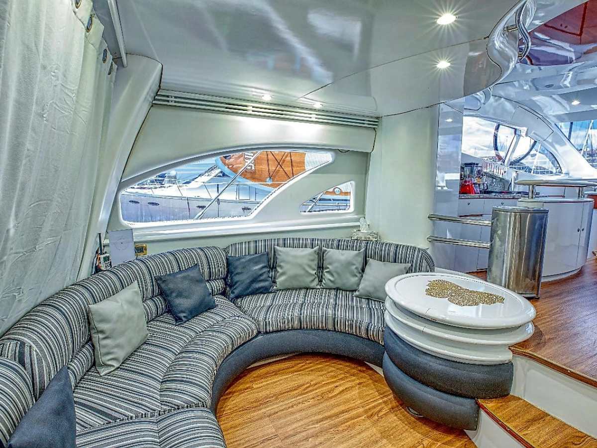 Luxurious yacht interior with curved gray couch and round white table.