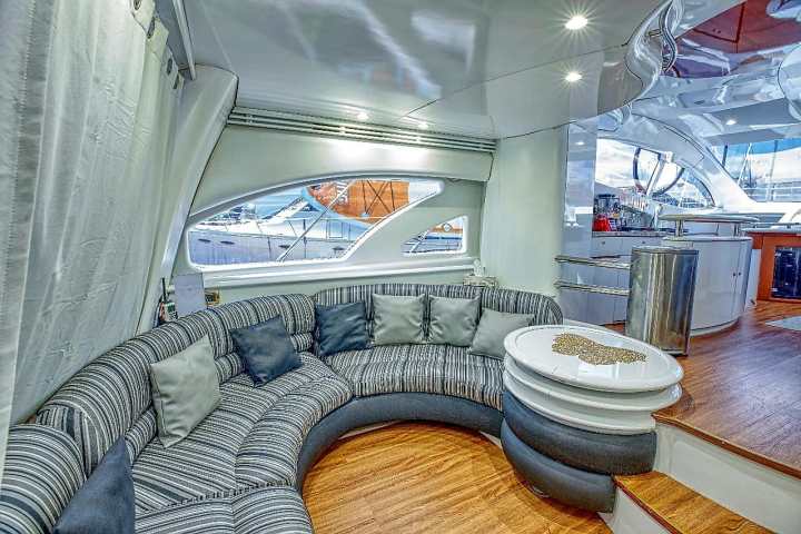 Luxurious yacht interior with curved gray couch and round white table.