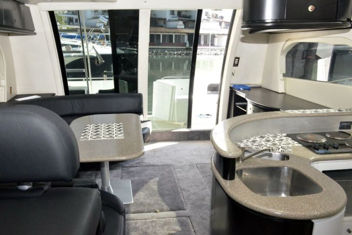 Modern boat interior with seating, kitchenette, and large windows.