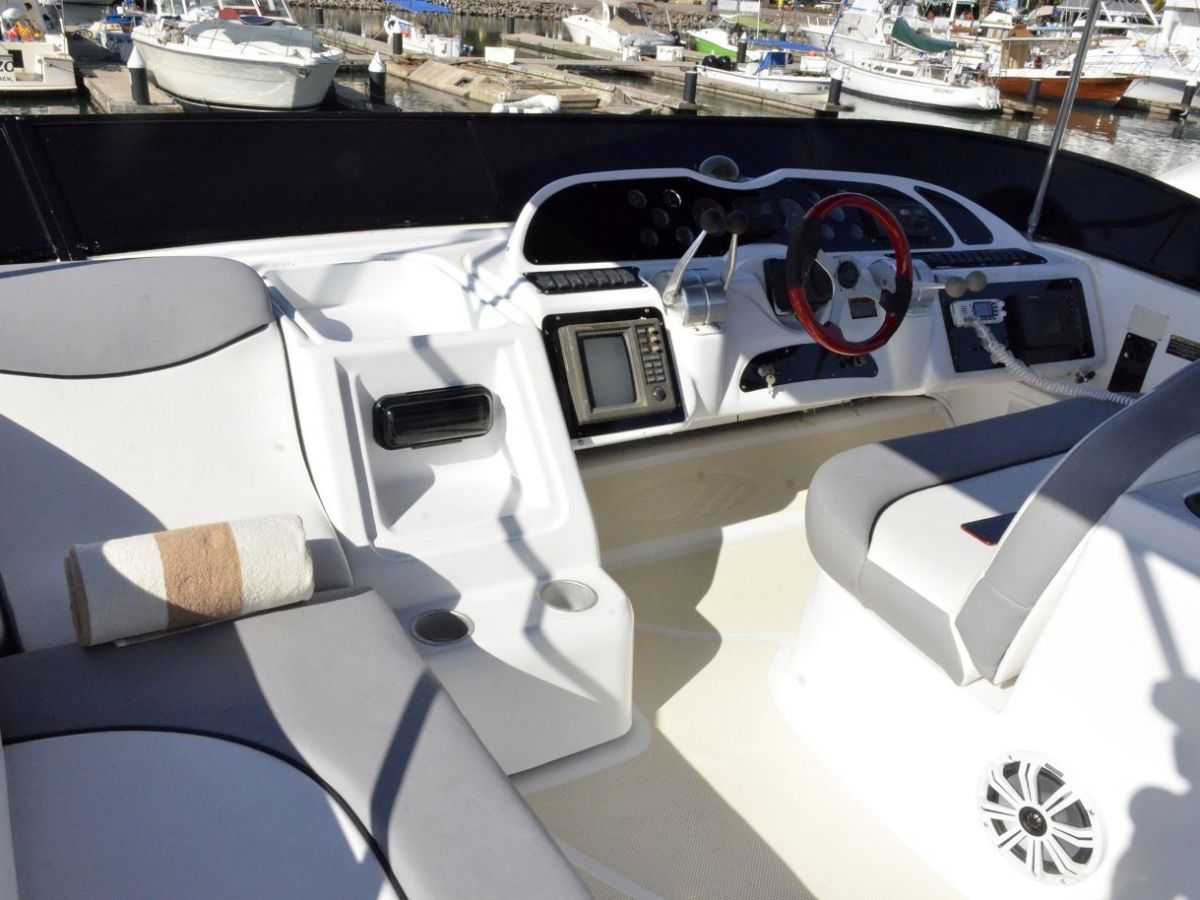 Interior of a boat cockpit with steering wheel and navigation equipment.