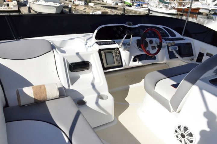 Interior of a boat cockpit with steering wheel and navigation equipment.