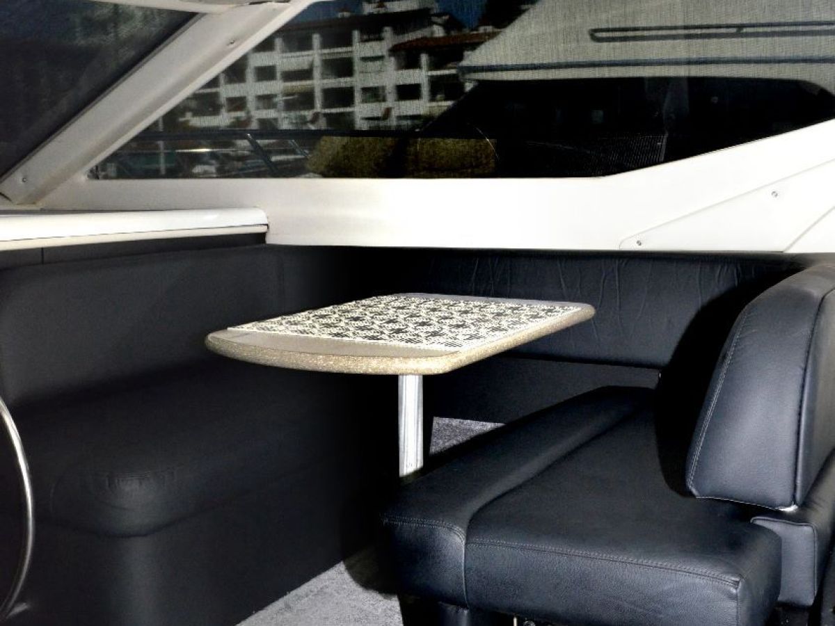 Interior of a yacht with a seating area, table, and control panel.