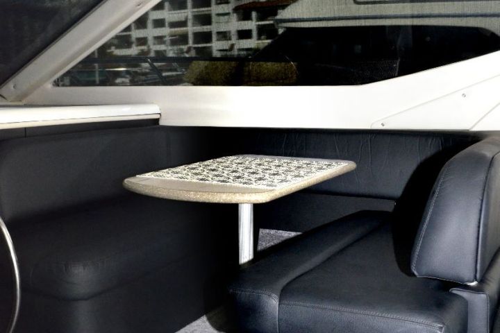 Interior of a yacht with a seating area, table, and control panel.