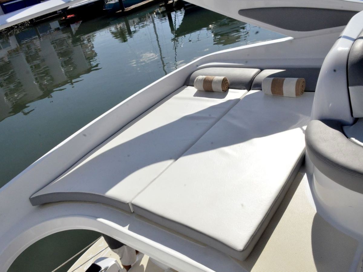 Boat sun deck with cushions and water view.