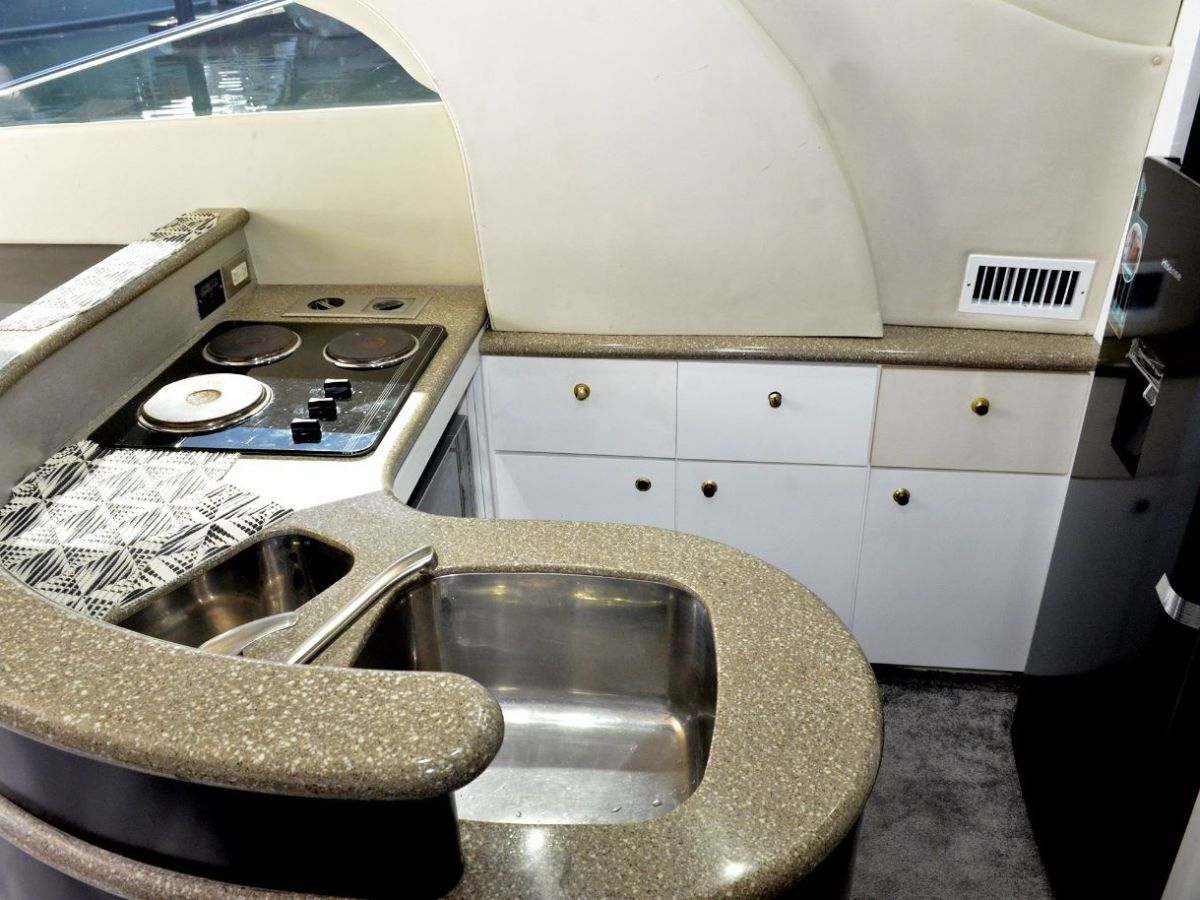 Compact yacht kitchen with stove, sink, and curved counter.