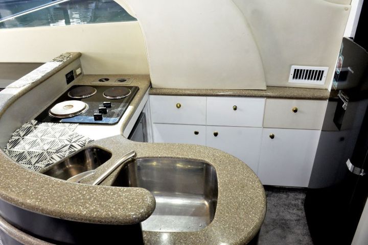 Compact yacht kitchen with stove, sink, and curved counter.