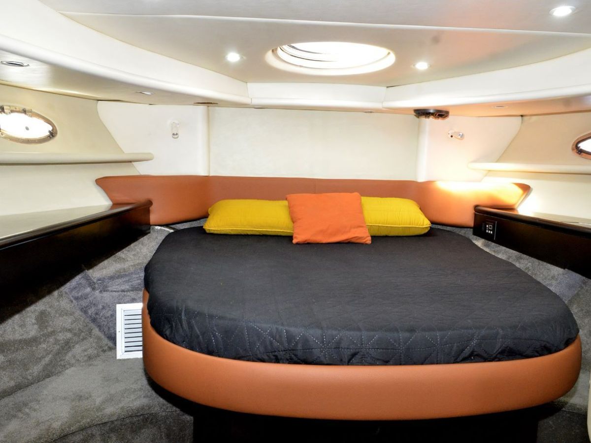 Cozy boat cabin with a circular bed, orange and yellow pillows.