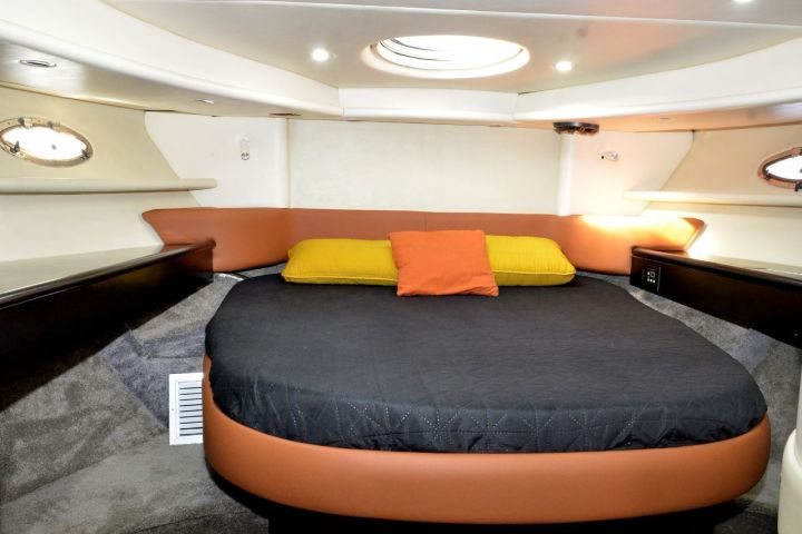 Cozy boat cabin with a circular bed, orange and yellow pillows.
