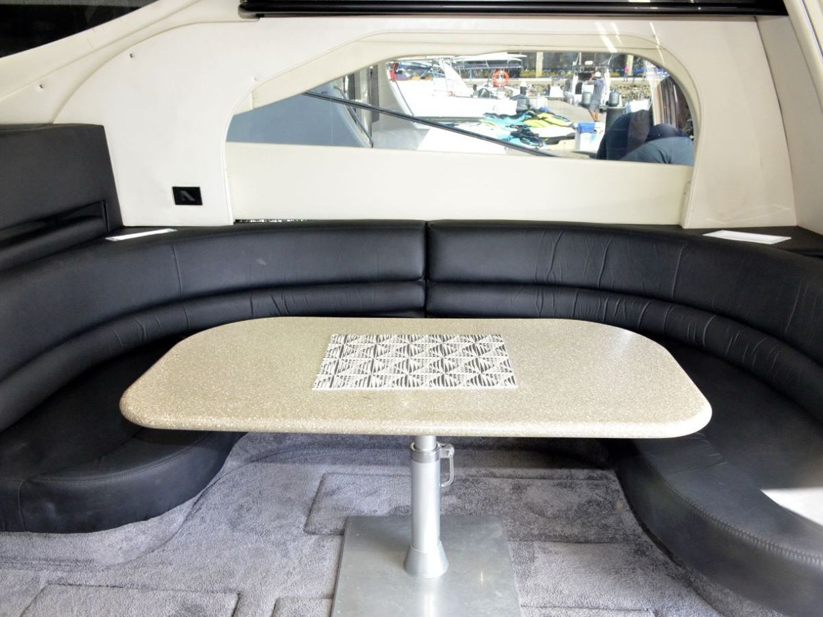 Luxurious boat interior with curved sofa and table, modern design.