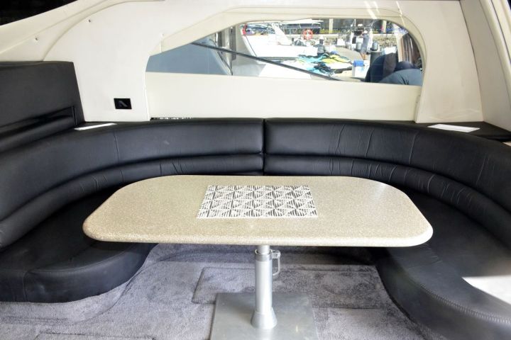 Luxurious boat interior with curved sofa and table, modern design.
