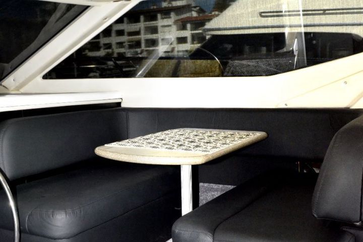 Boat interior with black seats, small table, and control panels.