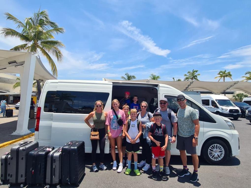 a group of people standing in front of a car posing for the camera
