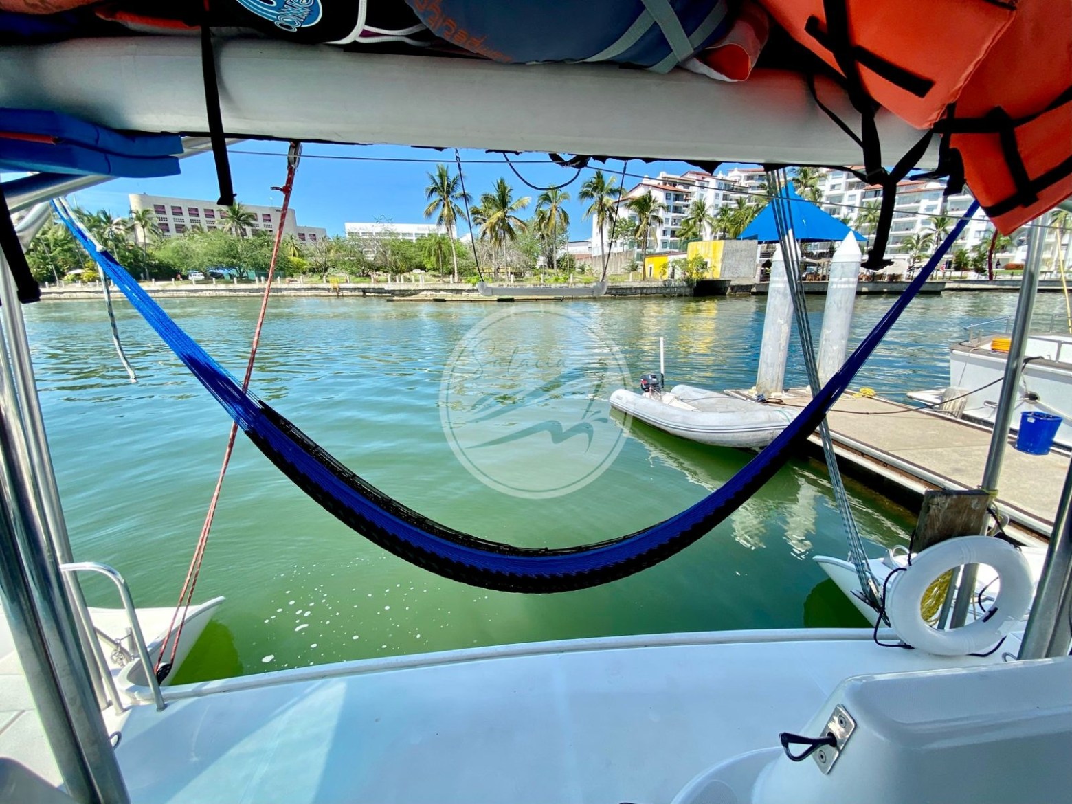 Hammock hanging on a boat with a view of the marina and palm trees.
