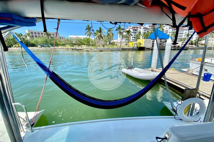 Hammock hanging on a boat with a view of the marina and palm trees.