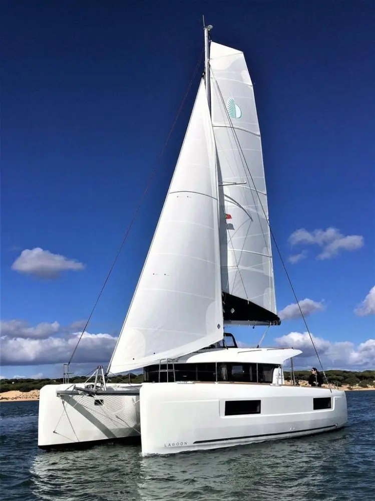 White sailing catamaran with blue sky and clouds in the background.