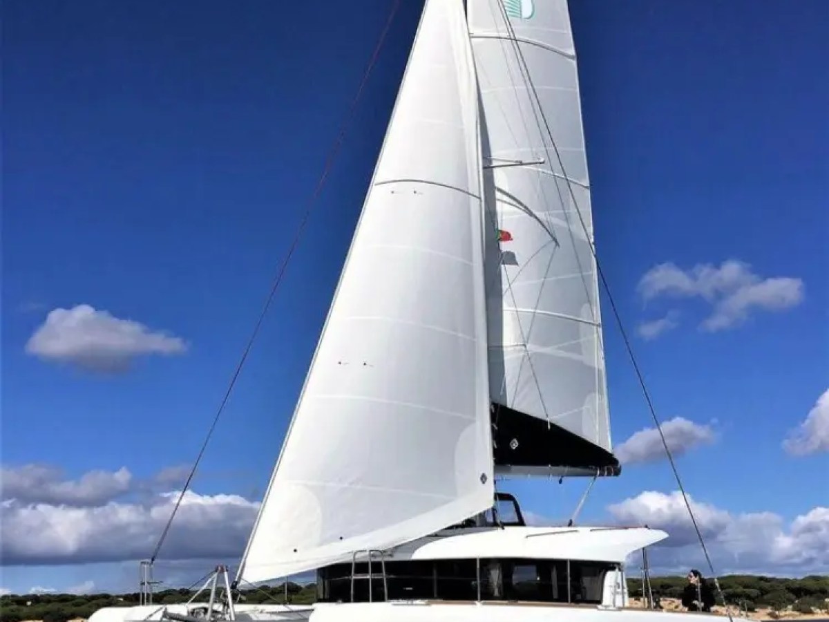 White sailing catamaran with blue sky and clouds in the background.