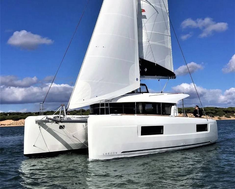 White catamaran sailing on a sunny day with blue sky and clouds.
