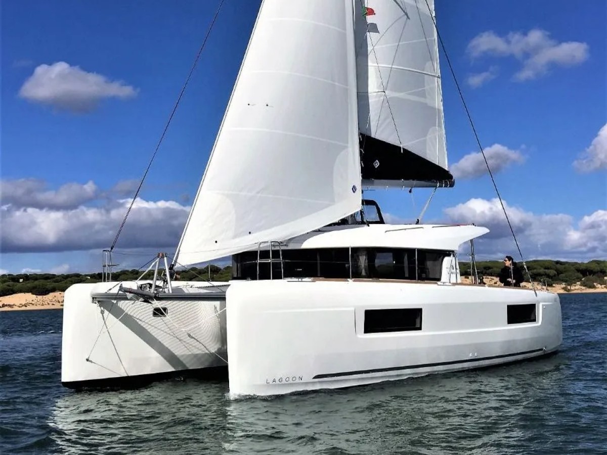 White catamaran sailing on a sunny day with blue sky and clouds.
